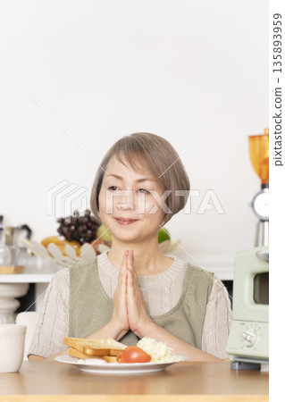 Senior woman toasting bread and eating breakfast in the kitchen Senior woman toasting bread and eating breakfast in the kitchen 135893959