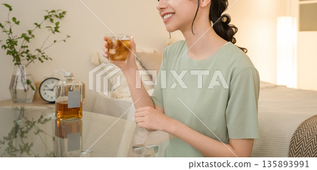 Young Asian woman having a drink in the bedroom at home (whisky, home drinking, drinking habits) Young Asian woman having a drink in the bedroom at home (whisky, home drinking, drinking habits) 135893991