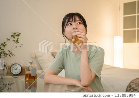 年輕的亞洲女性在家中臥室喝酒(威士忌、家庭飲酒、飲酒習慣) 年輕的亞洲女性在家中臥室喝酒(威士忌、家庭飲酒、飲酒習慣) 135893994