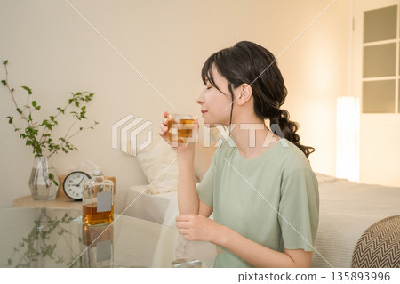 Young Asian woman having a drink in the bedroom at home (whisky, home drinking, drinking habits) Young Asian woman having a drink in the bedroom at home (whisky, home drinking, drinking habits) 135893996