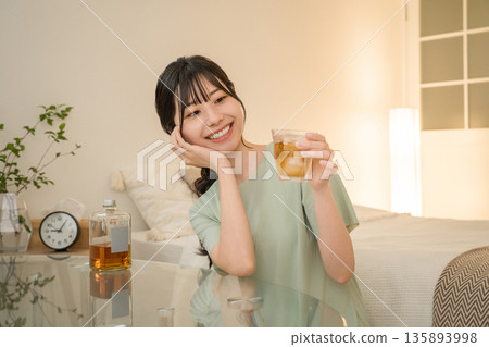 Young Asian woman having a drink in the bedroom at home (whisky, home drinking, drinking habits) Young Asian woman having a drink in the bedroom at home (whisky, home drinking, drinking habits) 135893998