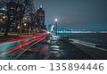 The waterfront promenade is lined with street lamps creating a dramatic contrast with the moving car light trails 135894446
