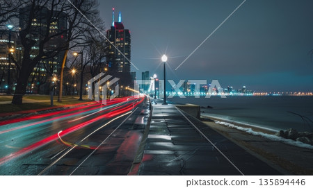 The waterfront promenade is lined with street lamps creating a dramatic contrast with the moving car light trails 135894446