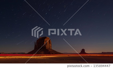 The stillness of the desert is broken by the energetic light trails of cars near the iconic monoliths 135894447