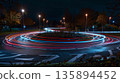 The circular design of a roundabout is accentuated by the sweeping curves of light trails from passing cars 135894452