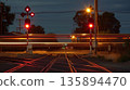 A striking display of light trails from passing vehicles and the train itself creates a lively atmosphere at a rural train crossing 135894470
