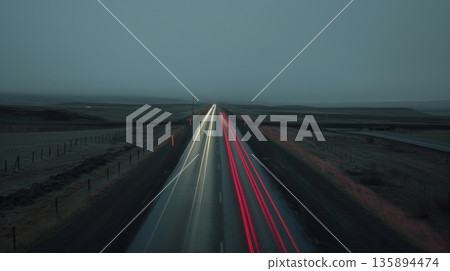 The lonely highway is enlivened by a blur of red and white car light trails a reminder of life once bustling through this deserted area 135894474