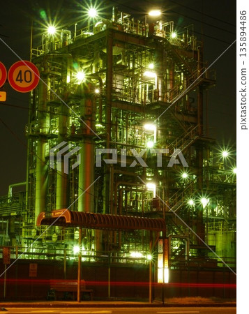 Bus stop at night and a complex, shining factory plant. January 25, 2015, Kawasaki City, Japan. 135894486