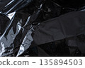 Crumpled dark metallic foil texture with sharp reflective folds 135894503