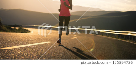 Woman runner running in sunset mountain road 135894726