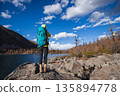Backpacking woman taking photo with a digital camera on autumn high altitude mountain top 135894778