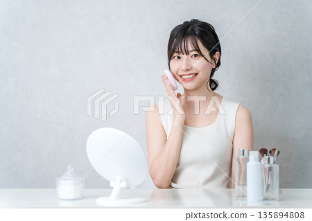Smiling Asian woman applying foundation powder makeup 135894808
