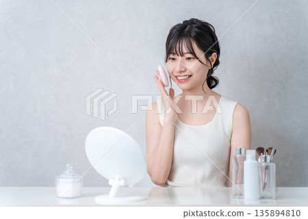 Smiling Asian woman applying foundation powder makeup 135894810