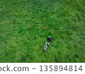 Aerial view of woman riding mountain bike on flowering grassland mountain trail 135894814