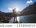 Backpacking woman taking photo with a digital camera on autumn high altitude mountain top 135894819