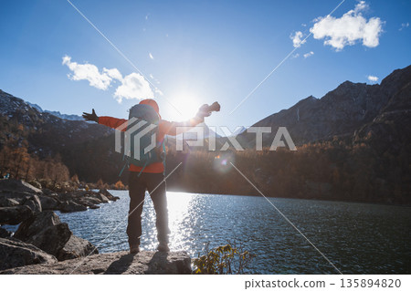 Happy backpacking woman photographer on autumn high altitude mountains Happy backpacking woman photographer on autumn high altitude mountains 135894820