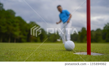 Golf ball is on a green lawn in a beautiful golf course with morning sunshine. Golf ball is on a green lawn in a beautiful golf course with morning sunshine. 135894982