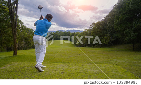 Golfer playing golf in the evening golf course, on sun set evening time. Golfer playing golf in the evening golf course, on sun set evening time. 135894983