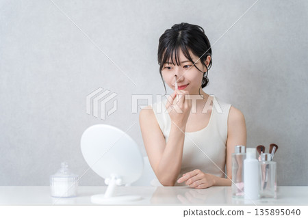 一位女士正在用化妝刷塗抹鼻影和高光等化妝品。 135895040