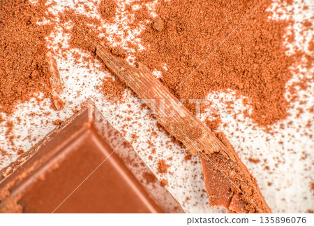 Milk chocolate pieces with cocoa powder on white background 135896076