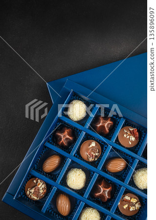 Assorted chocolate candies in blue box on dark background with copy space Assorted chocolate candies in blue box on dark background with copy space 135896097