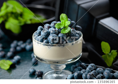 Panna cotta with fresh blueberries in a clear bowl. 135896165