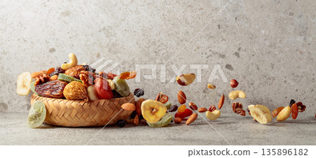 Mix of dried fruits and nuts in motion on a gray background. Mix of dried fruits and nuts in motion on a gray background. 135896182