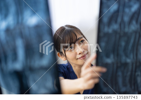 一位身穿藏藍色醫用工作服的年輕日本女子正在查看X光片。 135897743