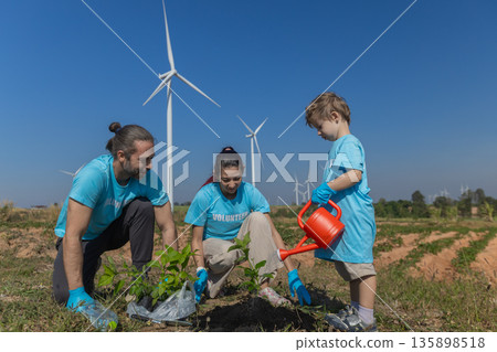 Family helping planting tree in garden for save world on wind turbine field background Family helping planting tree in garden for save world on wind turbine field background 135898518