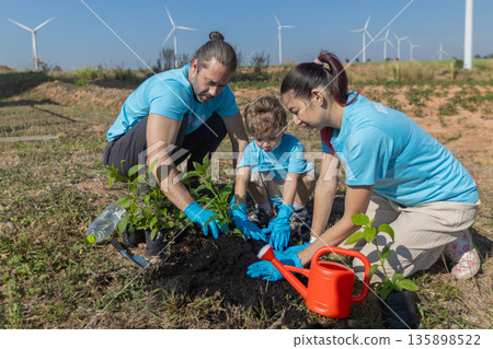 Family helping planting tree in garden for save world on wind turbine field background Family helping planting tree in garden for save world on wind turbine field background 135898522