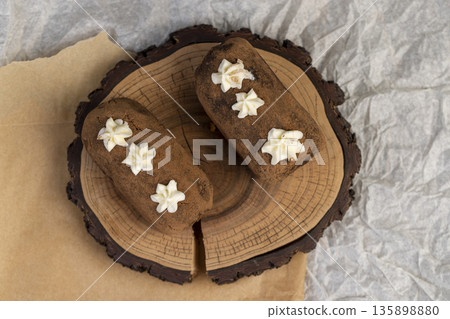 a black potato cake lies on a paper, a sweet classic cake made from butter and a large amount of cocoa mixed with sponge cake and cognac a black potato cake lies on a paper, a sweet classic cake made from butter and a large amount of cocoa mixed with sponge cake and cognac 135898880