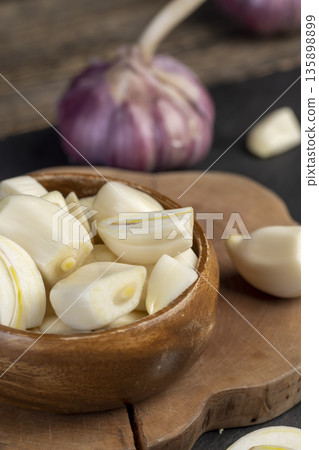 peeled and sliced purple garlic on the black kitchen table and peeled and sliced fragrant fresh and natural garlic spices scattered on the kitchen table during cooking peeled and sliced purple garlic on the black kitchen table and peeled and sliced fragrant fresh and natural garlic spices scattered on the kitchen table during cooking 135898899