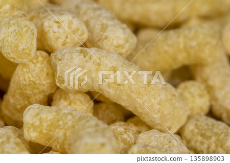 yellow sweet sticks of corn flour with added sugar for quick cooking with milk or yogurt, ready-to-eat corn sticks scattered on food paper yellow sweet sticks of corn flour with added sugar for quick cooking with milk or yogurt, ready-to-eat corn sticks scattered on food paper 135898903