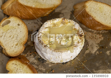 oven-fried round white cheese in a mold with pieces of fried crispy baguette with spices, delicious cheese with mold and wheat flour baguette with natural spices oven-fried round white cheese in a mold with pieces of fried crispy baguette with spices, delicious cheese with mold and wheat flour baguette with natural spices 135898910