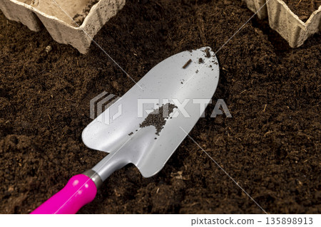 basil seeds and earth-filled cardboard pots for seedlings with fertile brown soil, basil seeds and paper disposable cups for seedlings filled with soil mixed with humus 135898913