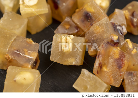 fresh Turkish delight sprinkled with a small amount of powdered white sugar, cubic sweet white soft pieces of Turkish delight with nuts and dried fruits, yellow-orange sweetness 135898931