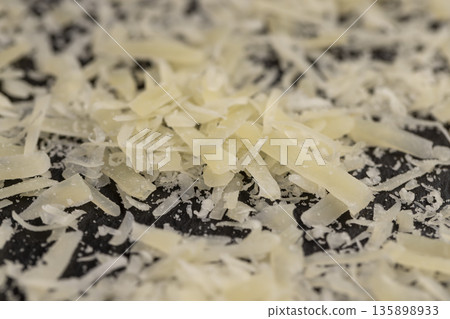 hard ripe cheese grated into small pieces for pasta or pizza, grated piece of yellow quality cheese as an ingredient for a large dish 135898933