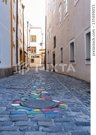 Passau, Germany - Apr 16, 2025: The very narrow, historic hell alley in the old town of Passau, Germany. Passau, Germany - Apr 16, 2025: The very narrow, historic hell alley in the old town of Passau, Germany. 135899055