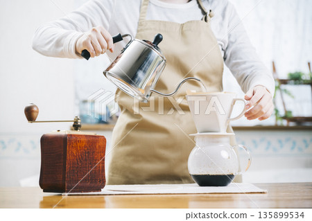 一位女士正在往咖啡杯裡倒咖啡 135899534