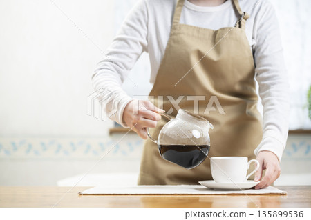 Woman pouring coffee into a coffee cup 135899536