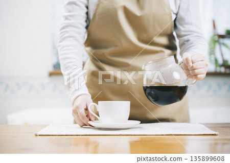 一位女士正在往咖啡杯裡倒咖啡 135899608