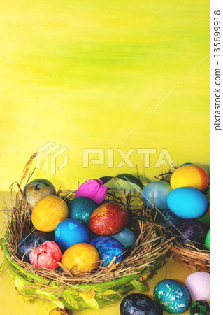 Colorful easter eggs in a basket on a yellow wooden table. Vertical photo Colorful easter eggs in a basket on a yellow wooden table. Vertical photo 135899918