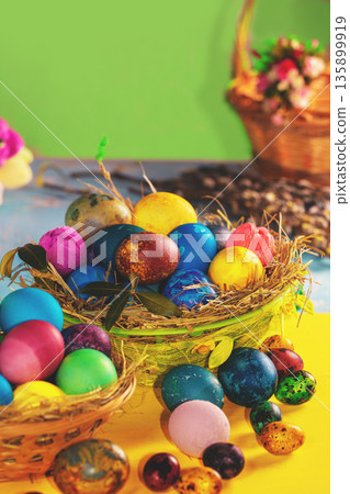 Colorful easter eggs in a basket on a yellow wooden table. Vertical photo Colorful easter eggs in a basket on a yellow wooden table. Vertical photo 135899919
