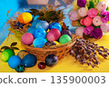 Colorful easter eggs in a basket on a yellow wooden table 135900003