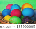 Colorful easter eggs in a basket on a wooden table 135900005
