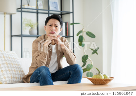 A middle-aged man worries in the living room A middle-aged man worries in the living room 135901047