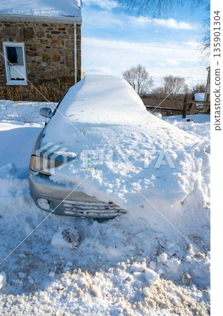 Siilver car buried in snow in rural setting blue sky Siilver car buried in snow in rural setting blue sky 135901304