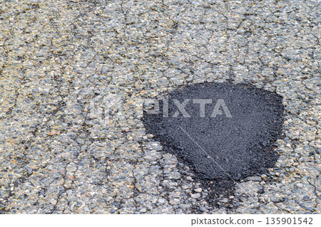 Fresh asphalt patch. Roadwork. Patched asphalt road. Asphalt patch temporary road repair work Fresh asphalt patch. Roadwork. Patched asphalt road. Asphalt patch temporary road repair work 135901542