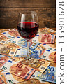Wine glass stands on money at bar during wine sale event in IA 135901628