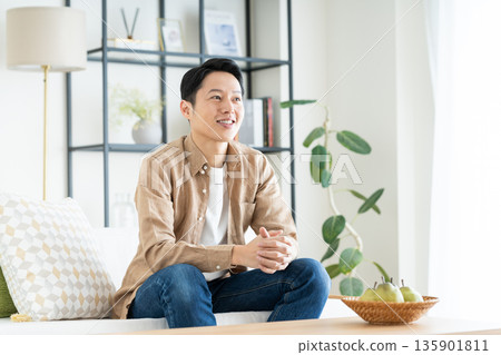 A middle-aged man relaxing in the living room 135901811